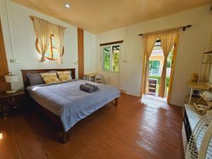 a bedroom with a bed and a wooden floor at Baan suan khun ta บ้านพักสวนคุณตา in Ko Chang