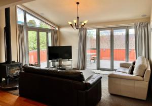 a living room with a leather couch and a television at Kaltech House - Lake Tekapo in Lake Tekapo