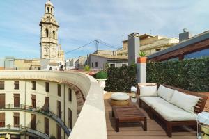 un balcone con divano e un edificio con torre dell'orologio. di Valencia Luxury - Boutique Redonda a Valencia