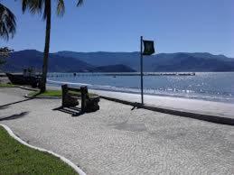 two benches sitting on a sidewalk near the water at Praia Suítes Itagua Ubatuba in Ubatuba