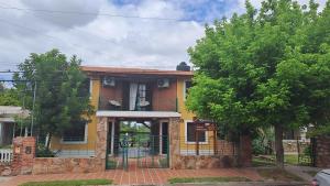 a yellow house with a fence in front of it at Complejo NONA RITA in Villa Cura Brochero