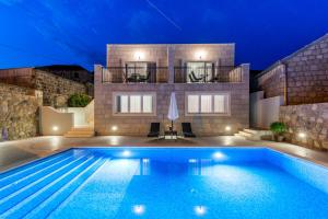 a villa with a swimming pool in front of a house at Apartments Villa Kabalero in Gruda