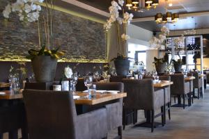 a restaurant with wooden tables and chairs and plants at Fletcher Hotel Het Veluwse Bos in Beekbergen