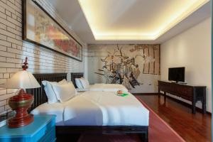 a bedroom with a large white bed and a desk at GRAND JOLi贝尊琳卡客栈 in Baisha