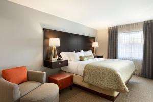 a hotel room with a bed and a chair at Staybridge Suites Midland by IHG in Midland