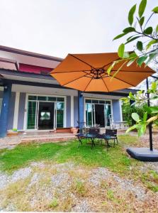 a large orange umbrella in front of a house at BaanRatsitornHomestay in Langu
