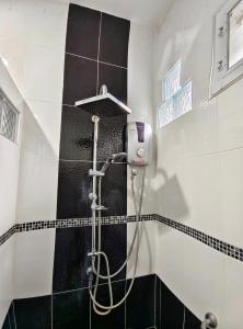a shower in a bathroom with black and white tiles at BaanRatsitornHomestay in Langu +22 photos