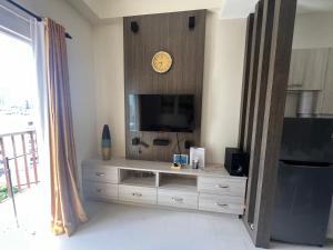 a living room with a television and a clock on a wall at City Center 1-bedroom with balcony and washer in Cebu City