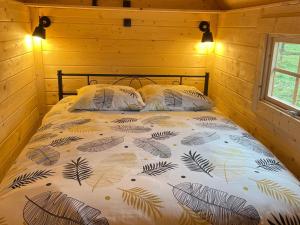 a bedroom with a bed with a bedspread with leaves at Kota finlandais avec bain nordique privatif et ferme pédagogique - FR-1-410-457 in Cérans-Foulletourte