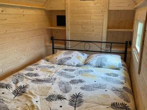 a bed in a room with a wooden wall at Kota finlandais avec bain nordique privatif et ferme pédagogique - FR-1-410-457 in Cérans-Foulletourte