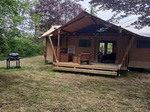une tente brune avec une terrasse dans un champ dans l'établissement Cabane Trappeur Lodge avec Jacuzzi et Ferme Pédagogique - FR-1-410-458, à Cérans-Foulletourte