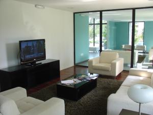 sala de estar con muebles blancos y TV de pantalla plana en Jardines del Country, en Punta del Este