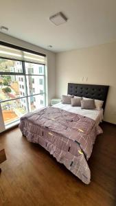 ein Schlafzimmer mit einem großen Bett mit einem großen Fenster in der Unterkunft Nuevo Estudio de Lujo en el corazón de San Miguel in La Paz