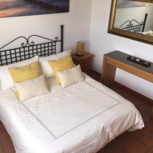 Cama blanca con almohadas amarillas y espejo en Las Rosas Apartment (Adults Only) en Punta de Mujeres