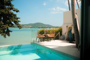 a patio with a table and chairs next to the water at Beachfront Secret Tides Villa Sol in Koh Samui 