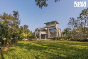 an exterior view of a house with a large yard at StayVista's Greystone Estate with Pool, Terrace, and Snooker Table in Lonavala