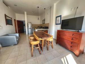 a living room with a wooden table and a kitchen at Apartment 2 Maleconcito del Sol Barra de Navidad in Barra de Navidad