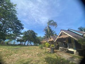 ein Haus mit einer Palme neben einem Feld in der Unterkunft Ingdao Bungalow Koh Chang อิงดาว บังกะโล เกาะช้าง in Ko Chang