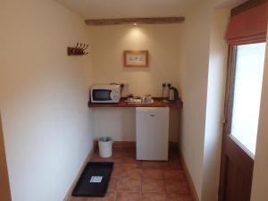 a small kitchen with a microwave and a refrigerator at The Courtyard, Laurel Farm in Lowestoft