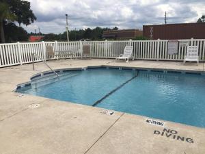 una piscina con 2 sillas y una valla blanca en Americas Best Value Inn & Suites Brunswick, en Brunswick