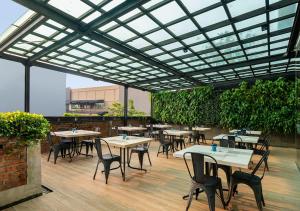 an outdoor patio with tables and chairs and plants at PRIME PARK Hotel & Convention Pekanbaru in Pekanbaru