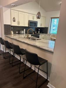 默特尔比奇Exquisite 3 bedroom, 3 bath villa - 19E West Hyde Park - Kingston Plantation villa的厨房设有酒吧、椅子和水槽