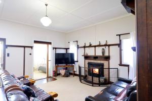 un soggiorno con divani in pelle e camino di Heritage Home with BBQ & Outdoor Fire Pit a Tenterfield