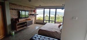 a bedroom with a bed and a tv and a window at Casa Boutique Abadia de Tomine in Guatavita