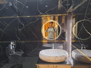 a woman taking a picture of herself in a bathroom mirror at Hotel The Shivraat in Rishīkesh