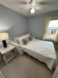 a white bedroom with a bed and a window at Colonels Quarters in Eastport
