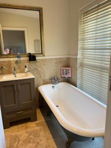 a bathroom with a tub and a sink and a mirror at Mont Vue Manor in Franschhoek