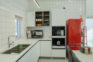 a kitchen with white cabinets and a red refrigerator at The Stay Christmas Yusuam in Jeju