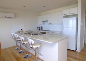 a kitchen with a counter with stools and a refrigerator at Elanora Tranquility at Emu Bay in Emu Bay
