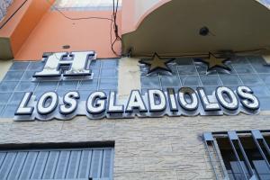 una señal para los gladios al lado de un edificio en Hotel Los Gladiolos, en Cajamarca