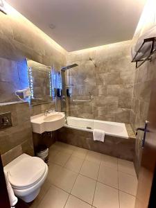 a bathroom with a toilet and a tub and a sink at Midtown Hotel & Suites in Beirut