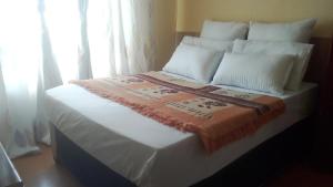 a bed with white pillows and a blanket on it at 33 On Swallows Guest House in Soshanguve