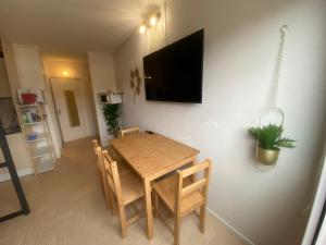 einen Esstisch mit Stühlen und einen TV an der Wand in der Unterkunft Studio au pied des pistes in Le Dévoluy