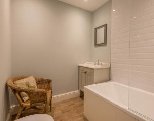a bathroom with a tub and a sink and a chair at Carn Du 1 in Padstow +15 photos