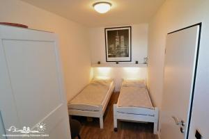 a small room with two beds and a door at 29 Ferienwohnung Stranddistel App. 56-409 in Burg auf Fehmarn +3 photos