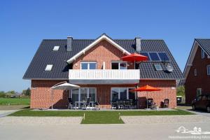 una casa de ladrillo rojo con sombrillas y sillas en 28 Fehmarn An der Reiterkoppel 49b EG, en Burg auf Fehmarn