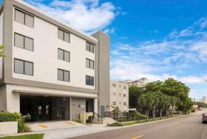 a white building on a street with a car parked in front at Stylish Studio Miami Suite Oasis Near Calle Ocho & Brickell in Miami