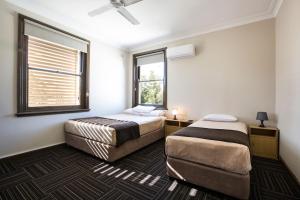 two beds in a room with two windows at Toongabbie Hotel in Blacktown