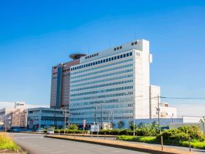 un edificio de oficinas alto con una carretera delante en FLEXSTAY INN Kashima Central, en Kamisu