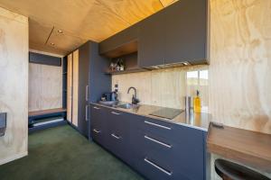 a kitchen with blue cabinets and a sink at Tukare Cabins in Te Anau