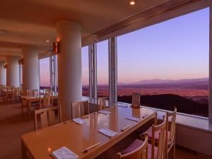 a restaurant with tables and chairs and a large window at Shin Furano Prince Hotel in Furano