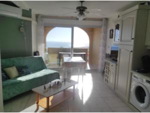 a living room with a green couch and a table at Vue Mer Panoramique WIFI gratuit in Le Barcarès +25 photos