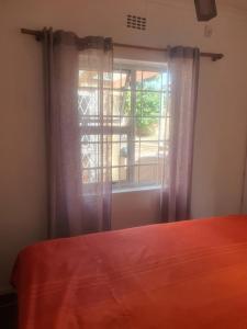 een slaapkamer met een bed en een raam bij Lifestyl Cottage in Cape Town