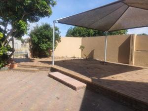 een patio met een parasol en een bank bij Lifestyl Cottage in Cape Town