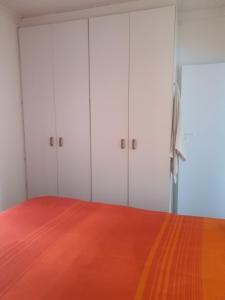 een slaapkamer met witte kasten en een oranje vloer bij Lifestyl Cottage in Cape Town