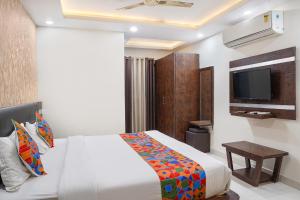 a bedroom with a white bed and a tv at FabHotel Jalsa DLX in Bhopal